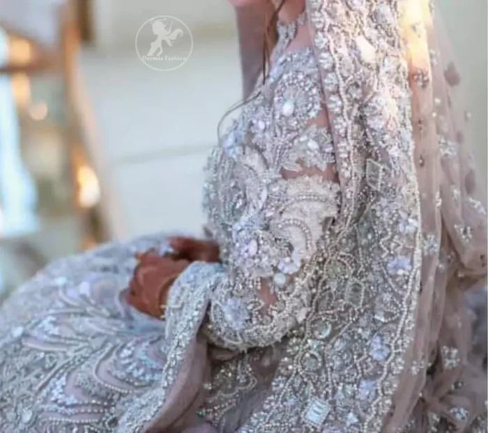 The grand gold bridal stands out due to its uniqueness and the perfect fusion of modern cut and traditional embroidery. This dress is beautifully decorated with heavy embroidery. It is highlighted with kora, dabka, tilla, sequins and pearls. Style it up with embellished wait belt. It comes with brocade pajama. It is coordinated with tissue dupatta which is sprinkled with sequins all over it. It is further furnished with four sided thick embellished border.