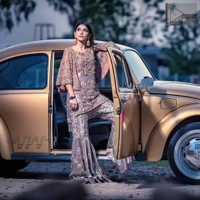 Tradition meets modernity. This outfit is stunningly perfect for any evening ensemble. This dress is beautifully sculptured with floral embroidery, adorned with bell sleeves embellished with antique shaded kora, dabka, pearl, sequins and multiple color resham embroidery all over. The bottom of the shirt is enhanced with rich zardosi embroidery and finishing with tassels at the end. It comprises with fully embellished gharara. Pair it up with matching dupatta ornamented with scattered tiny floral motifs and sequins.
