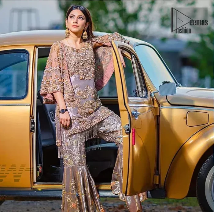 Tradition meets modernity. This outfit is stunningly perfect for any evening ensemble. This dress is beautifully sculptured with floral embroidery, adorned with bell sleeves embellished with antique shaded kora, dabka, pearl, sequins and multiple color resham embroidery all over. The bottom of the shirt is enhanced with rich zardosi embroidery and finishing with tassels at the end. It comprises with fully embellished gharara. Pair it up with matching dupatta ornamented with scattered tiny floral motifs and sequins.