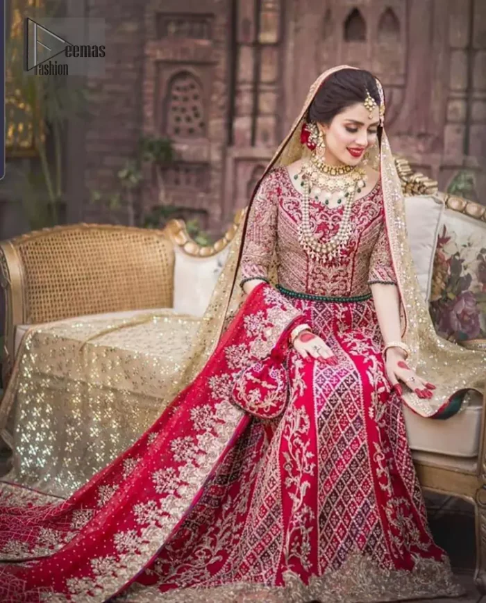 A bed of red roses translated onto a dress decorated, elaborate and flamboyant elegance. This bridal wear is perfect for your big day. The bridal stands out due to its uniqueness and the perfect fusion of modern cut and traditional embroidery. The blouse is beautifully ornamented with floral embroidery and swarovski crystals lines. Finishing with green dangling beads ball at the end. Pair it up with beautiful embroidered lehenga adorned with golden kora, dabka, tilla and sequins. Furthermore it is highlighted with geometric patterns and applique details on lehenga. It is coordinated with beautiful dupatta with thick matha patti border on two sides and intricate thin border on remaining two sides.