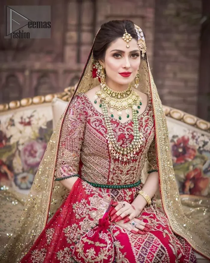 A bed of red roses translated onto a dress decorated, elaborate and flamboyant elegance. This bridal wear is perfect for your big day. The bridal stands out due to its uniqueness and the perfect fusion of modern cut and traditional embroidery. The blouse is beautifully ornamented with floral embroidery and swarovski crystals lines. Finishing with green dangling beads ball at the end. Pair it up with beautiful embroidered lehenga adorned with golden kora, dabka, tilla and sequins. Furthermore it is highlighted with geometric patterns and applique details on lehenga. It is coordinated with beautiful dupatta with thick matha patti border on two sides and intricate thin border on remaining two sides.