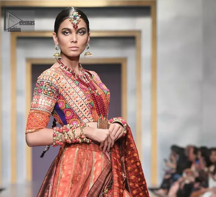 This dress is majestic beauty and perfect for mehndi mayon day. Delicately crafted and personifying chic elegance with an element of grandiose. A full heavily embellished blouse with multiple color resham thread embroidery and mirror work details. Having half sleeves adorned with mirror work. It comprises with self printed lehenga finishing with dull golden lace at the end. Style it confidently with chocolate brown dupatta with thick embellished border on the front and comparatively lighter work border on long edges. Medium and tiny sized ornamental motifs scattered all-over.