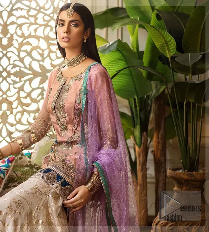 Add some super cool twist to your look with this outfit on your nikah. Gussy up in this luxuriously designed shirt emboldened with intricate embroidery along with beautiful rich patterns and delicate applique details at the daaman. Furthermore this super stunning shirt is made of rich floral embroidery which is further enhanced with zardosi work. Having full length sleeves adorned with scalloped finishing. Style it up with artfully coordinated ivory sharara finessed with lace and applique details at the bottom. The outfit is beautifully coordinated with light purple dupatta with embellished lace borders on all four sides and scattered sequins all over.