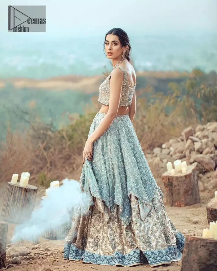 This bridal dress executing heavily hand crafted art of zardosi, kora and dabka with splashes of golden and silver is a classical visit to feminine personification. The heavenly handcrafted lehenga showcases the traditional art of zardozi, nakshi, kundan, kora and dabka; adorning the intricate and meticulous hand embellishments giving it a wholesome gentle stance paired with a regal gold sleeveless blouse. The bottom of the lehenga is enhanced with embellished applique with zardosi work and resham embroidery. It comprises with organza dupatta having four sided matha patti style border and scattered sequins all over it.