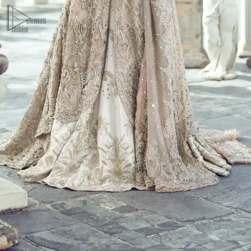 Captured in traditional silhouette, The bridal stands out due to its uniqueness and the perfect fusion of modern cut and traditional embroidery. It is highlighted with silver and light golden kora, dabka, tilla, sequins and pearls. It comes with heavily embellished front open back trail gown ornamented with floral embroidered motifs and geometric patterns. Paired up with ivory lehenga done with light gold embroidery. It is coordinated with chiffon dupatta which is sprinkled with sequins all over it. It is further furnished with four sided border.