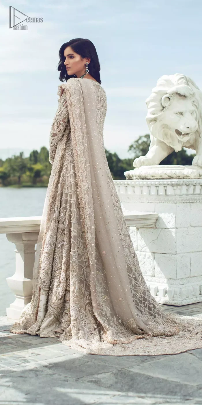 Captured in traditional silhouette, The bridal stands out due to its uniqueness and the perfect fusion of modern cut and traditional embroidery. It is highlighted with silver and light golden kora, dabka, tilla, sequins and pearls. It comes with heavily embellished front open back trail gown ornamented with floral embroidered  motifs and geometric patterns. Paired up with ivory lehenga done with light gold embroidery. It is coordinated with chiffon dupatta which is sprinkled with sequins all over it. It is further furnished with four sided border.