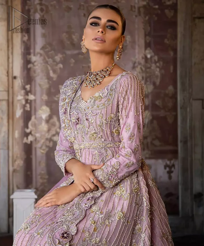 Exude elegance and class in this back trail maxi finessed with beautiful embellishment. The outfit is beautifully sculptured with floral embroidery, adorned with vertical lines and fixed waist belt embellished with silver and light golden kora, dabka, tilla and sequins work all over. The back of the outfit has an artistically designed motif. The outfit is styled with a hand embellished crystal belt. It comprises with cigarette pants and light pink net dupatta ornamented with sprinkled sequins on the ground and four sided light border.