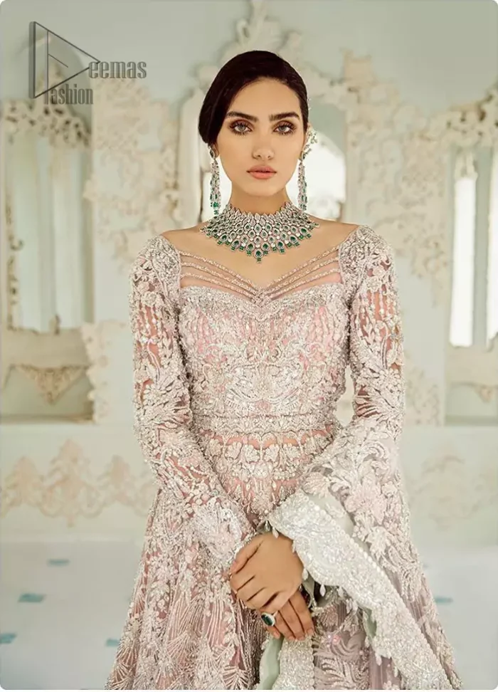 An example of beauty and elegance. Look breathtakingly stylish in this embroidered regalia furnished with intricate embroidered neckline. This ethereal maxi highlights the collision of heritage and beauty of traditional zardosi craftsmanship with modern chic silhouette. Beautifully designed sleeves is an amalgamation of geometric and floral design elements. The light pink net dupatta with chann and scalloped applique border all around the edges makes the look complete.