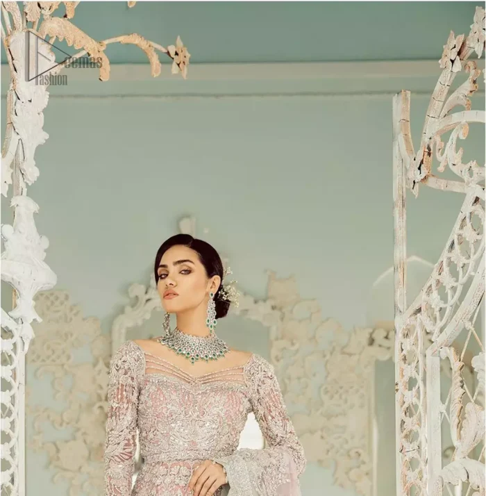 An example of beauty and elegance. Look breathtakingly stylish in this embroidered regalia furnished with intricate embroidered neckline. This ethereal maxi highlights the collision of heritage and beauty of traditional zardosi craftsmanship with modern chic silhouette. Beautifully designed sleeves is an amalgamation of geometric and floral design elements. The light pink net dupatta with chann and scalloped applique border all around the edges makes the look complete.