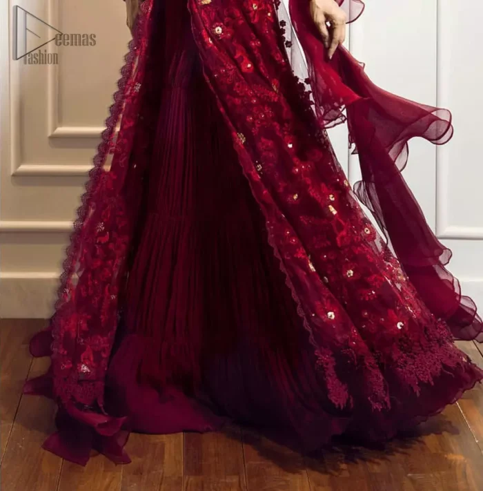 This exceptionally detailed front open gown lehenga is cut in a seductive fit and flare silhouette that’s sure to turn heads on your big day. The bodice with plunging V-neckline is adorned in richly floral lace with fabulous sparkle. Furthermore the bodice is highlighted with golden zardozi work and floral applique. Center slits and bottom of the gown is beautifully decorated with floral lace. It is coordinated with maroon crushed lehenga and organza dupatta. 