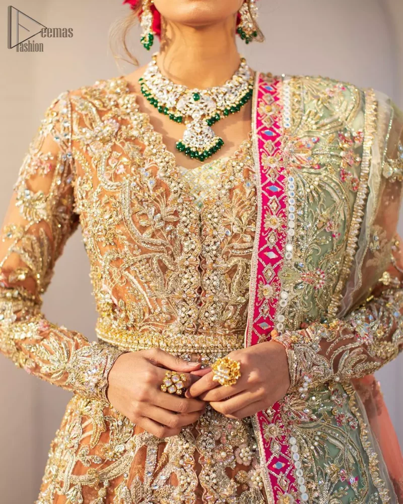 Captured in traditional silhouette, The bridal stands out due to its uniqueness and the perfect fusion of modern cut and traditional embroidery. This front open short frock is highlighted with kora, dabka, tilla, sequins and pearls. It comes with full embellished lehenga adorned with floral bunches, applique on the hemline and sequins spray all over it. It is coordinated with organza dupatta which is sprinkled with tiny floral motifs all over and a thick embellished border on all four sides with applique details.