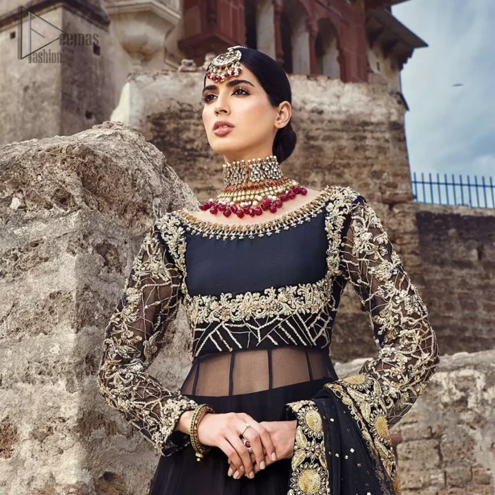 Delicately crafted and personifying chic elegance with an element of grandiose. This regal black outfit is an immensely captivating traditional piece, enhancing the art of classical heritage showcasing the craftsmanship of golden kora, dabka, tilla detailed with sequins and pearls; artistically embellished to give a beautiful rhythm to the outfit. Furthermore the anarkali frock is enhanced with fascinating embellishment on neckline and frilled hemline. It comes with an exquisite black lehenga with thick embroidered bottom to give it a regal look. It comes with a black net dupatta with sequins sprayed all over finished with thick embellishment all around the edges.