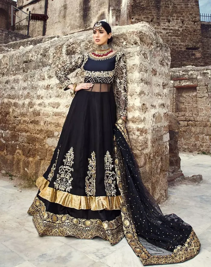 Delicately crafted and personifying chic elegance with an element of grandiose. This regal black outfit is an immensely captivating traditional piece, enhancing the art of classical heritage showcasing the craftsmanship of golden kora, dabka, tilla detailed with sequins and pearls; artistically embellished to give a beautiful rhythm to the outfit. Furthermore the anarkali frock is enhanced with fascinating embellishment on neckline and frilled hemline. It comes with an exquisite black lehenga with thick embroidered bottom to give it a regal look. It comes with a black net dupatta with sequins sprayed all over finished with thick embellishment all around the edges.