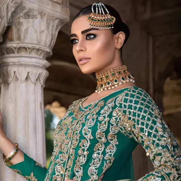 Steal the moment with our emerald green floor length angrakha emphasized with traditional neckline and intricate floral daman enhanced with light golden kora, dabka and sequins. The detailed zardosi work on sleeves and vertical panel stripes ornamented with gold kora and dabka embroidery on the bodice, the thick borders and floral bunches refined the classical royal look. Style it up with organza dupatta adorned with four sided kiran.