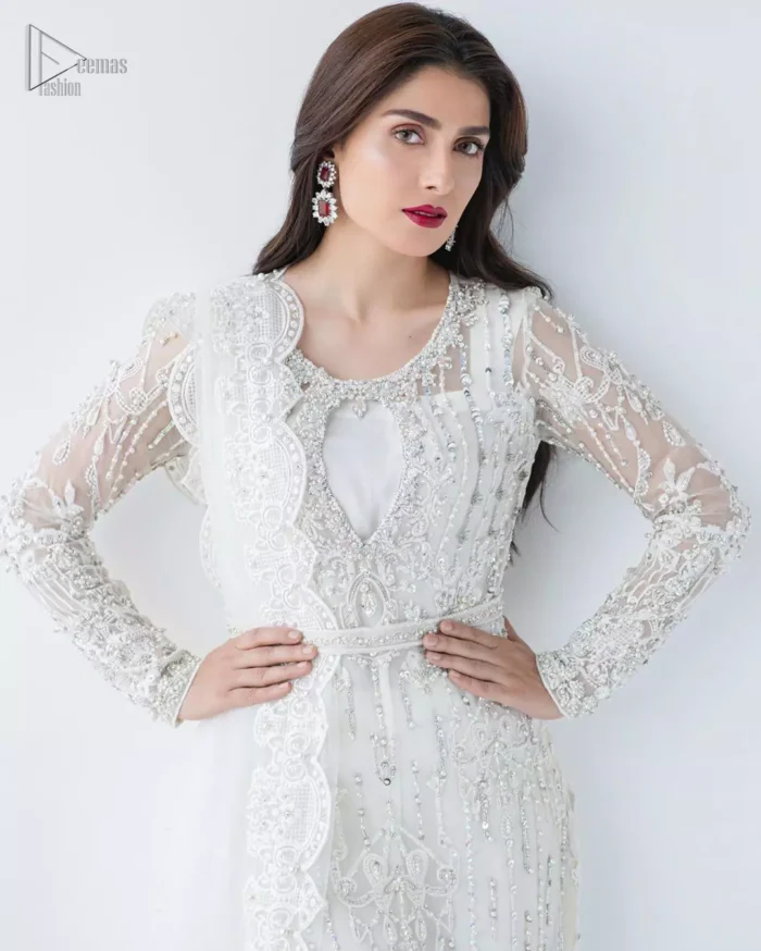 This is an ensemble that deserves to be flaunted. The ivory white shirt is an example of remarkable handiwork. With a lot of attention to detail, the intricate sequencing using glass beading and threads makes the shirt look like nothing but a dream. Furthermore the shirt is enhanced with thick embellished scalloped hemline. Sharara is magnificently decorated with scattered crystals all over. Beautifully paired it up with ivory white dupatta having four sided scalloped border.