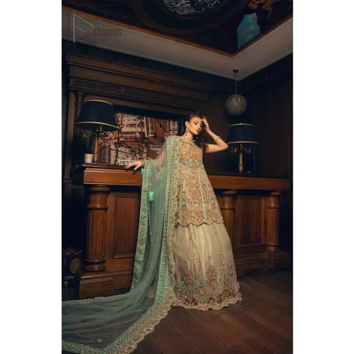 Classic, timeless and truly beautiful. Upholding the idea of simple is beautiful, you would definitely want to wear this outfit for your next occasion. The front open short frock is adorned with delicate arrangement of hand embellished floral patterns with multiple color thread embroidery and antique shaded zardozi work. The scalloped hemline done with champagne embellishment gives the right amount of glamour to the outfit. It coordinates with light fawn lehenga with scalloped bottom and heavy embellishment on it with zardozi. The look is completed with mint green organza dupatta with detailed work on the borders.