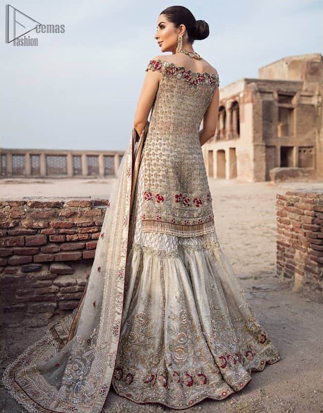 Classic and elegant, this dress is perfect for brides looking for a traditionally wedding outfit.. A perfectly pretty combination of light golden and antique embellishment, This off shoulder wedding dress is elegant and eye-catching in equal measure. This off shoulder shirt is done with zarozi detailing and vibrant floral motifs all over. Furthermore it is sculptured with different motifs like birds. It comprises with traditional handcrafted gharara. Complete the look with off white organza dupatta having four sided heavily embellished border and tassels.