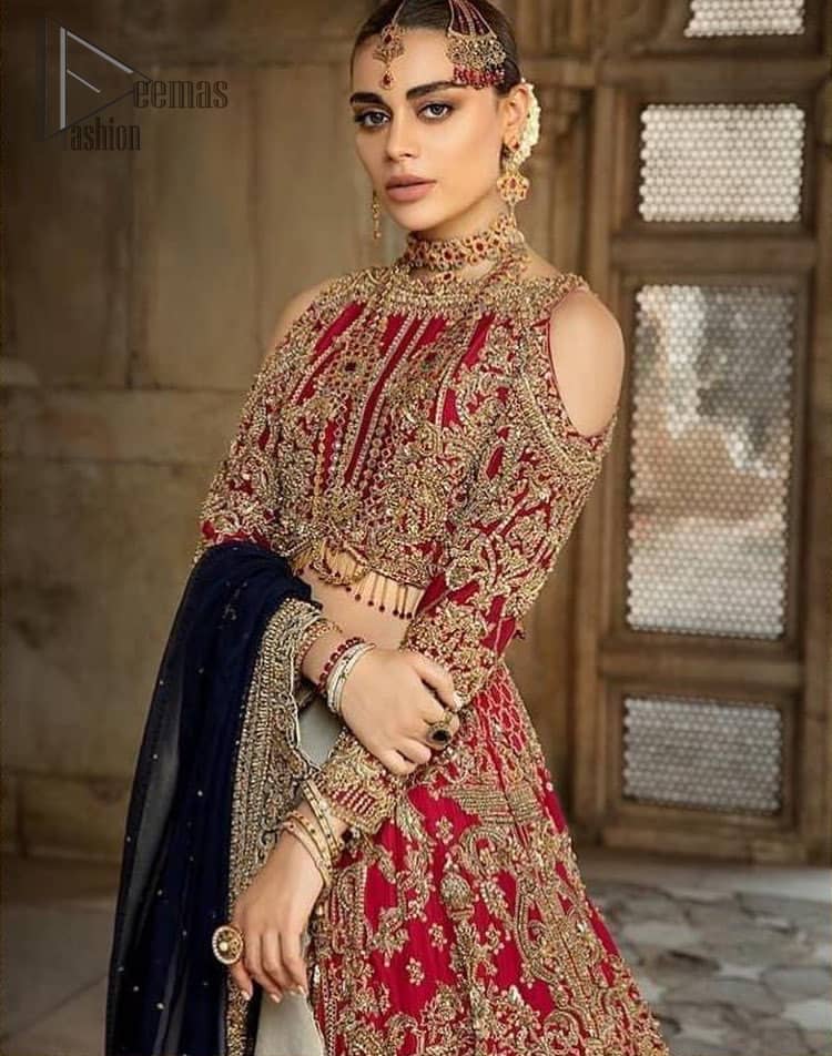 A breathtaking red traditional lehenga  paired with a detailed blouse, equally alluring make for an ensemble which is comfortably chic. The blouse is done with golden and antique shaded embroidery and finishing with tassels. Blouse having cold shoulder full sleeves. The lehenga is enhancing with the art of classical heritage showcasing the craftsmanship of kora, dabka, tilla, kundan and sequins detailed, artistically embellished to give a beautiful rhythm to the outfit. It comprises with navy blue dupatta sprinkled with sequins and four sided scalloped border. This is an ensemble that is sure to invite compliments galore.