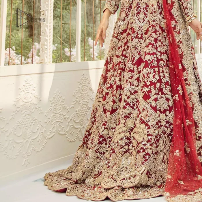This bridal dress is perfect for your big day. Our bride makes a statement in this stunningly floraison, perfect blend of glamour and tradition with outstanding craftsmanship and gorgeous detailing. This floor length maxi is beautifully sculptured floral jhaal, floral bunches and thick scalloped hemline done with light golden kora, dabka, tilla and sequins embroidery. Exude elegance with red lehenga finessed with beautiful embellished scalloped bottom with zardosi work. The red net dupatta with chann and finishing all around the edges makes the look complete.