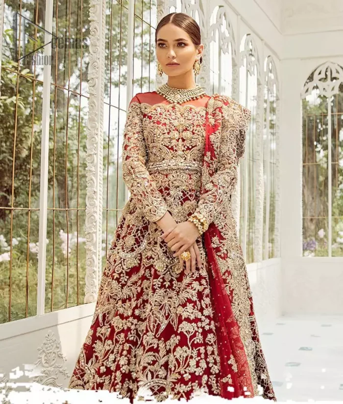 This bridal dress is perfect for your big day. Our bride makes a statement in this stunningly floraison, perfect blend of glamour and tradition with outstanding craftsmanship and gorgeous detailing. This floor length maxi is beautifully sculptured floral jhaal, floral bunches and thick scalloped hemline done with light golden kora, dabka, tilla and sequins embroidery. Exude elegance with red lehenga finessed with beautiful embellished scalloped bottom with zardosi work. The red net dupatta with chann and finishing all around the edges makes the look complete.