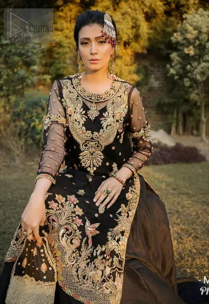 This elegant ensemble turns timeless piece into a chic fantasy. Steal the show with this endearing chiffon outfit with intricate yet rich embroidery. Artfully crafted neckline with detailed golden zardozi work. The hemline is ornamented with a central large motif and adorned with jaal. Furthermore, side slits are also decorated with floral embroidery and floral motifs are decorated with multiple color thread embroidery. The back is perfectly loaded with zardozi work. This outfit is comprises with black sharara and chiffon dupatta having sequins spray all over.