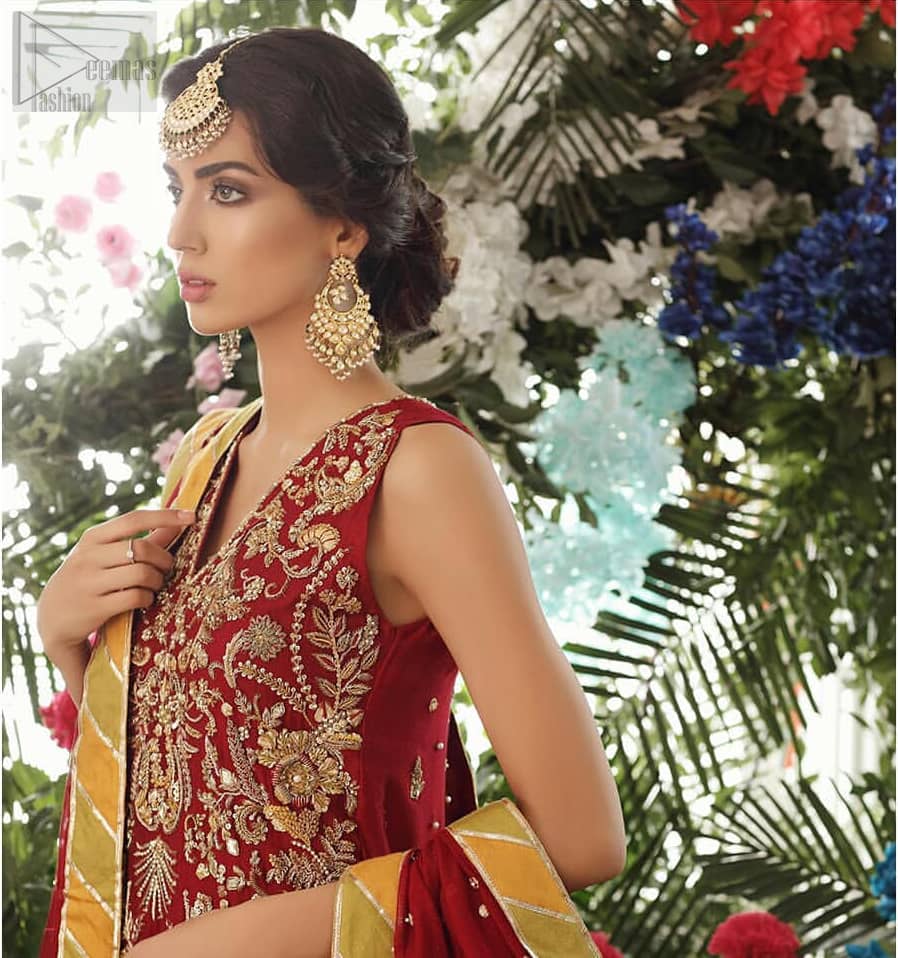 Tradition meets modernity. Boost your confidence and style in this glamorous attire accentuated with finest zardozi work embroidery and scalloped borders with dandling pearls. This maroon sleeveless shirt is ornamented with golden and light golden zardozi work. The scalloped hemline is decorated with dangling pearls. Style it confidently with maroon sharara adorned with beautiful gota work. It is paired with an ethereal maroon dupatta with scattered sequins all over and four sided applique borders.