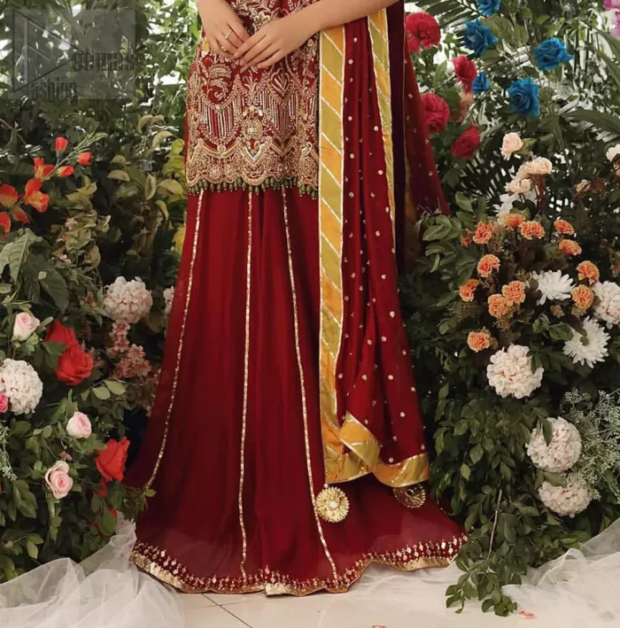 Tradition meets modernity. Boost your confidence and style in this glamorous attire accentuated with finest zardozi work embroidery and scalloped borders with dandling pearls. This maroon sleeveless shirt is ornamented with golden and light golden zardozi work. The scalloped hemline is decorated with dangling pearls. Style it confidently with maroon sharara adorned with beautiful gota work. It is paired with an ethereal maroon dupatta with scattered sequins all over and four sided applique borders.