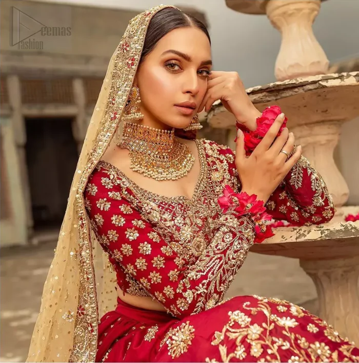 Our deep red bridal dress will make your special day even more perfect. Infused with classical glamour. Strike a breathtakingly elegant pose in this wedding dress. This artisan piece includes intricate hand embellishment. This highly skilled technique involves hand needle work to add beads and sequins to the fabric, giving your garments a unique look. The embroidery is done in the shades of light golden, antique and maroon thread work. The blouse is fully embellished and lehenga is adorned with floral details all over and thick embellished bottom. Furthermore the lehenga is also intensified with sprinkled floral motifs. Complete the look with golden net dupatta enhanced with sprinkled sequins on the ground and four sided embellished border.