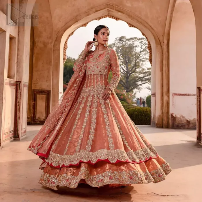 You are all set to make a lasting impact with the divine royalty of this dress. This garment is sure to make you look like glamorous with immaculate work covering every inch of the pishwas with multiple panels. This pishwas made of zardozi work with scalloped hemline and applique is everything that you need for your festivities. The brocade lehenga is beautifully adorned with thick embellished bottom with zardozi work in the shades of silver and gold. Style it up with peach organza dupatta with criss-cross patterns and floral booties on borders. This is an ensemble that deserves to be flaunted.