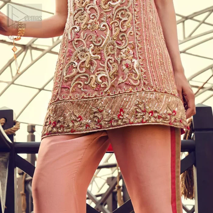 Delicately crafted and personifying chic elegance with an element of grandiose. You are all set to make a lasting impact with the divine royalty of this dress. The outfit is perfected with loaded dull golden, golden and antique work. The shirt is delicately hand crafted using the finest old age techniques and materials including kora, dabka, tilla, sequins and pearls. The back of the shirt is highlighted with cutwork embellishment. Furthermore it is also enhanced with thread embroidery. This outfit is comprises with peach raw silk bell bottom. Complete the look with peach organza dupatta decorated with sequins spray all over.