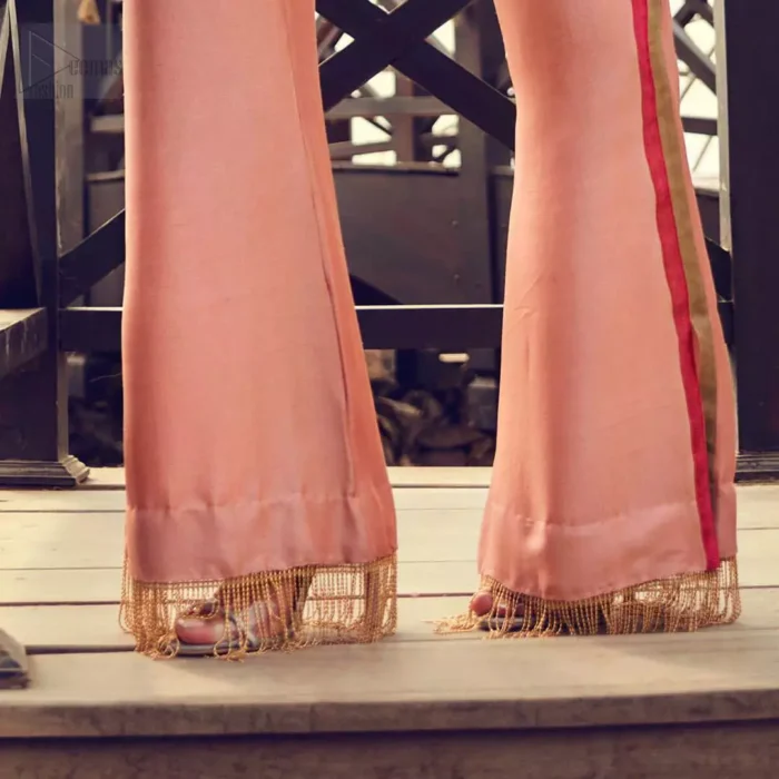 Delicately crafted and personifying chic elegance with an element of grandiose. You are all set to make a lasting impact with the divine royalty of this dress. The outfit is perfected with loaded dull golden, golden and antique work. The shirt is delicately hand crafted using the finest old age techniques and materials including kora, dabka, tilla, sequins and pearls. The back of the shirt is highlighted with cutwork embellishment. Furthermore it is also enhanced with thread embroidery. This outfit is comprises with peach raw silk bell bottom. Complete the look with peach organza dupatta decorated with sequins spray all over.