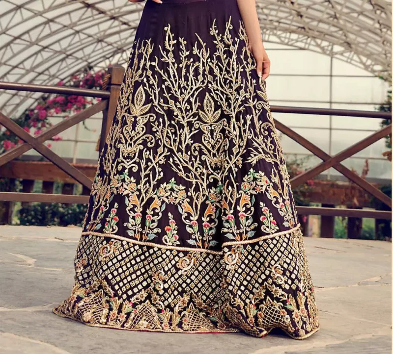 Captured in traditional silhouette, The bridal stands out due to its uniqueness and the perfect fusion of modern cut and traditional embroidery. This dress is beautifully decorated with heavy embroidery. It is highlighted with light golden kora, dabka, tilla, sequins and pearls. Blouse is fully enhanced with zardosi work and multiple color embroidery. It comes with full embellished lehenga adorned with floral booties and heavy embellished bottom. It is coordinated with plum organza dupatta which is sprinkled with sequins all over it.