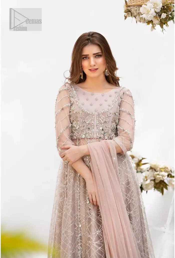 Embrace the season of festivities with this beautiful dress. Dazzle in this made to perfection, richly embroidered net outfit decorated with intricate embroidered front highlighted with silver and light golden zardozi work borders on daaman and embroidered stripes on sleeves. The bodice is fully furnished with zardozi work and sprinkled with floral motifs around neckline. The outfit is comprises with brocade sharara and tea pink net dupatta adorned with sequins spray all over.