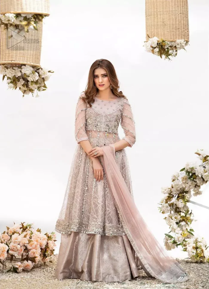 Embrace the season of festivities with this beautiful dress. Dazzle in this made to perfection, richly embroidered net outfit decorated with intricate embroidered front highlighted with silver and light golden zardozi work borders on daaman and embroidered stripes on sleeves. The bodice is fully furnished with zardozi work and sprinkled with floral motifs around neckline. The outfit is comprises with brocade sharara and tea pink net dupatta adorned with sequins spray all over.
