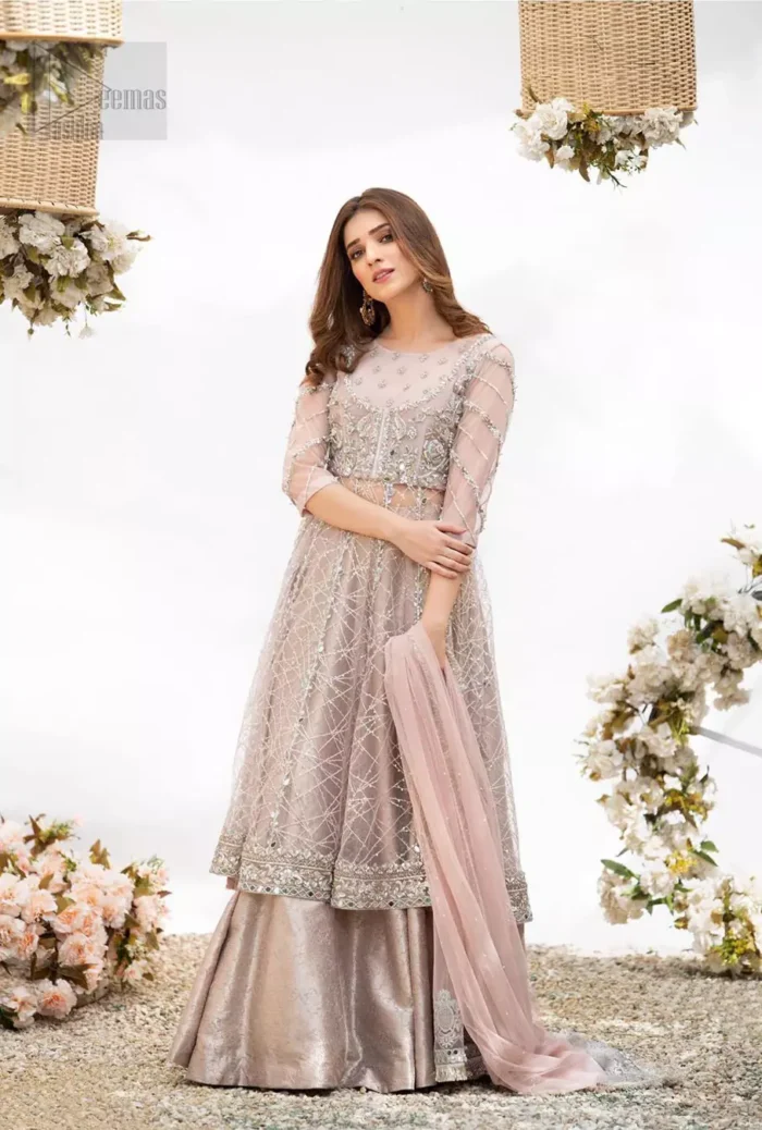 Embrace the season of festivities with this beautiful dress. Dazzle in this made to perfection, richly embroidered net outfit decorated with intricate embroidered front highlighted with silver and light golden zardozi work borders on daaman and embroidered stripes on sleeves. The bodice is fully furnished with zardozi work and sprinkled with floral motifs around neckline. The outfit is comprises with brocade sharara and tea pink net dupatta adorned with sequins spray all over.