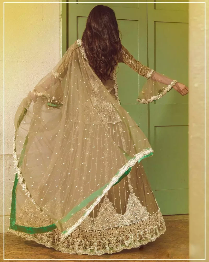 Let the crowd stare and make it worth their while when you walk wearing this outfit. Designed to flaunt your best features, the front open shirt carries intricate embellishment on the hemline and neckline. Complete the look with artfully coordinated lehenga which is ornamented with a bold and captivating design with a traditional intricate embroidery. Furthermore the lehenga and shirt is also emphasized with silver embroidered vertical lines. The fawn net dupatta with chann and scalloped finishing all around the edges makes the look complete. Upholding the idea of simple is beautiful, you would definitely want to wear this for your next occasion.