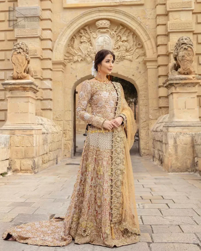 Strike a breathtakingly elegant pose in this wedding dress, designed with a beautiful blouse and a dramatic train. This artisan piece includes intricate hand-embellishment. This highly skilled technique involves hand needle work to add beads, kora, dabka, tilla and sequins to the fabric, giving our garments a unique look. The blouse is also enhanced with tassels on the hemline and back is adorned with horse shie neckline. Zardozi work is done in the shades of golden and silver. Dupatta is decorated with sequins spray on the canvas and finished with embroidered border on four sides which makes this outfit more beautiful.