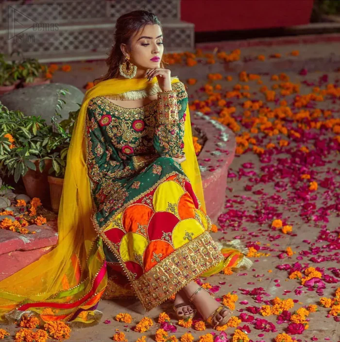 Beautifully elegant with a modern twist. This beautiful outfit comes with bottle green long shirt and colorful applique hemline, making an elegant, traditional and stylish mehndi dress. Excellence of craftsmanship is evident with intricate geometrical detailing that features the use of kora, dabka, crystals, sequins and glass beading. Furthermore it is enhanced with colorful floral motifs and golden zardozi work. It comprises with pink capri pants. Elegance is personified when it gets paired up with net dupatta with kiran on all sides and colorful strips on pallu.