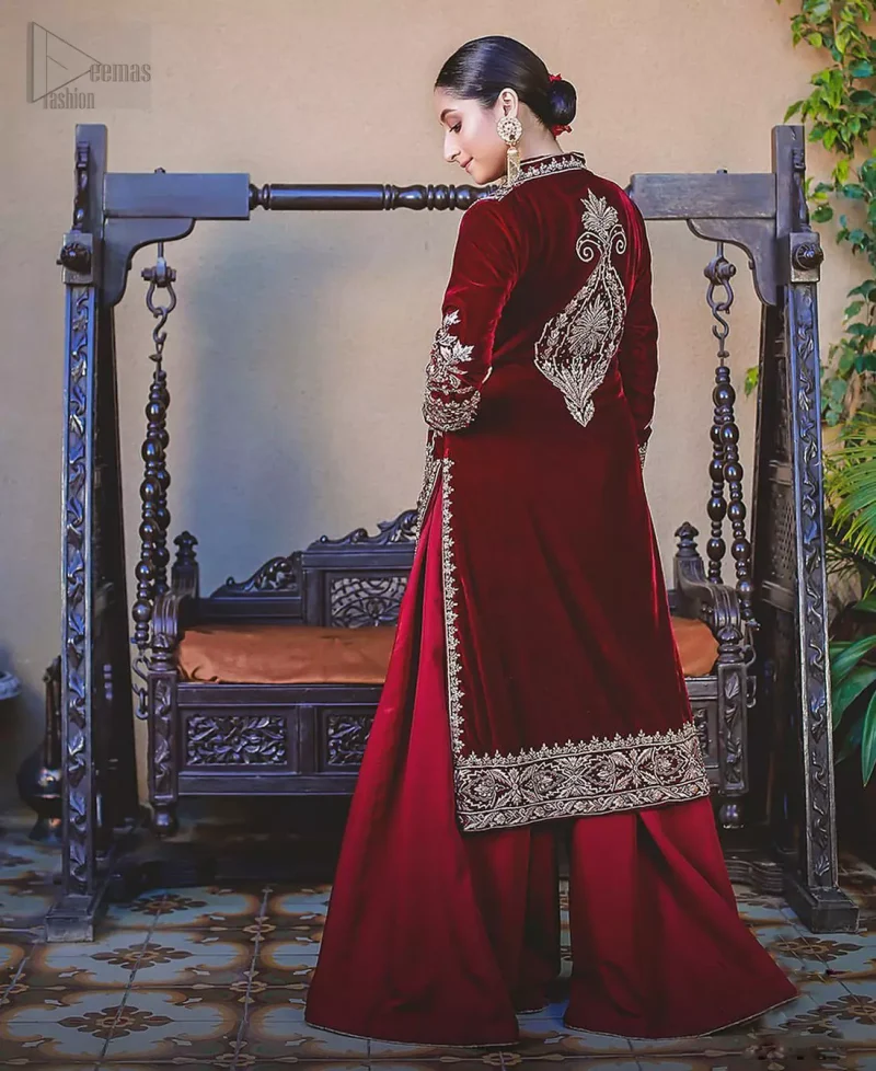 Steal the show with this endearing velvet outfit with intricate yet rich embroidery. The chic yet elegant front open shirt is decorated with embroidered patterns, embellished collar neckline and floral bunches. Hemline is even more enhanced with detailed zardozi work. The back of the shirt has a central large motif on the bodice while the zardozi work creates drama on both front and back panels. Beautifully paired up with maroon palazzo pants. Finish the look with maroon organza dupatta adorned with tiny floral motifs all over.