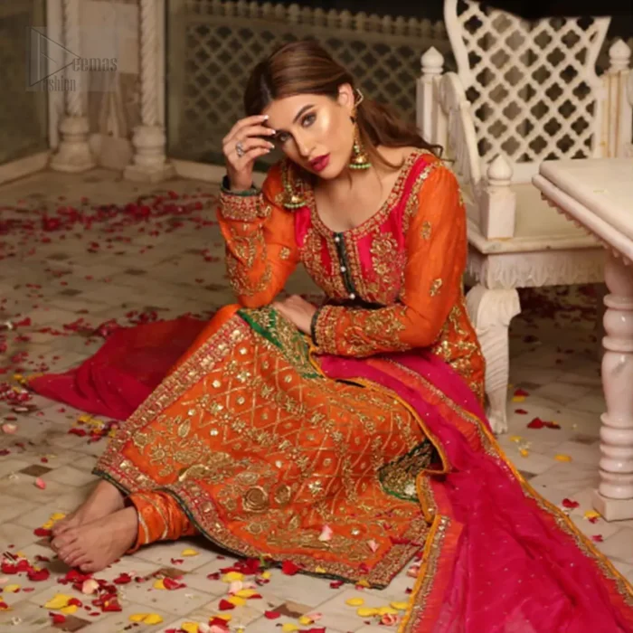 Get bold and beautiful with this uber-stylish ensemble that has flattering cuts, and a colour palette that is bewitching.  This orange long shirt adorned with intricate tilla work, kora, dabka and sequins is perfect ensemble for mehndi. Furthermore the shirt is also highlighted with pink embellished bodice and rest of the shirt is enhanced with geometric gota embroidery and green applique instantly draws attention.. It comprises with orange pajama adorned with gota work. Paired with pink chiffon dupatta with kiran lace finishing all around the edges that gives the right amount of glamour to the outfit.