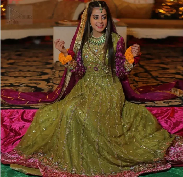 Nothing speaks of femininity and class louder than this mehndi outfits for bridesmaids. The sequinned whimsical florals embroidered across the flattering bodice in this ethereal frock is sure to turn heads in every room you walk into. The pairing of champagne zardozi work with parrot green fabric is an artist’s dream colour palette. The frock hemline is emphasized with banarsi applique details that gives perfect ending to this outfit. It comprises with matching tissue lehenga. The magenta organza dupatta with chann and gota work, finishing with kiran lace all around the edges makes the look complete. 