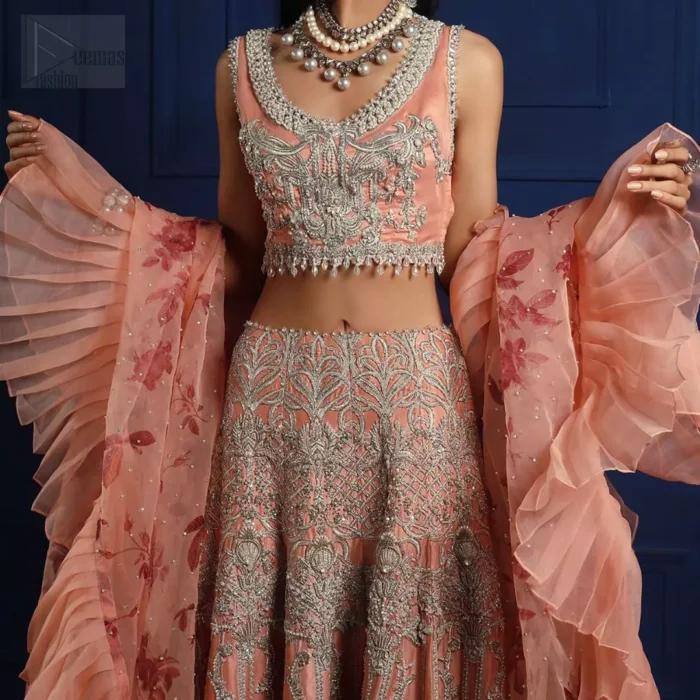 Crafted with love. This outfit is classically designed to make your memorable day beautiful as it should be. The peachy blouse is emphasized with intricate embroidery, handcrafted bootis adorned with silver embellishment finished with dangling pearls all around the edges. Compliment the look with flared lehenga which is decorated with silver kora, dabka, tilla and pearls work. Excellence of craftsmanship is evident with intricate detailing that features the use of zardozi work. The look is complete with organza dupatta finishing with frilled border.