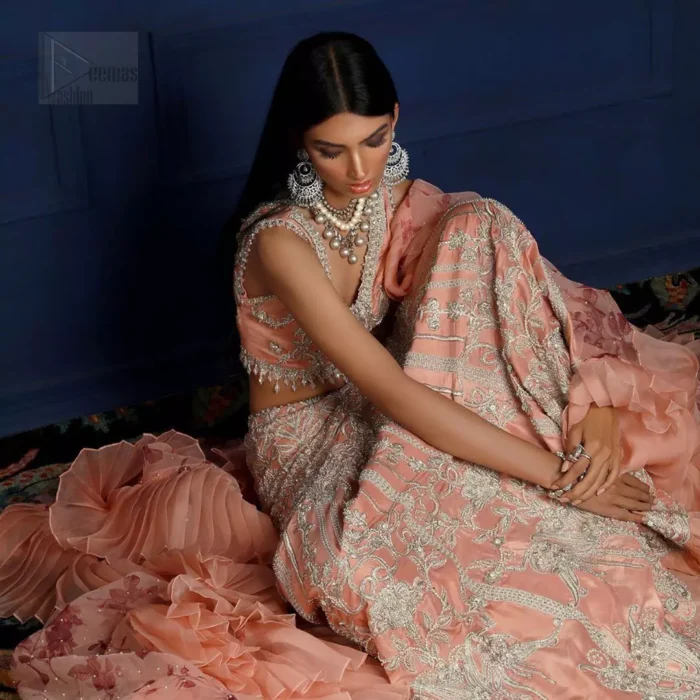 Crafted with love. This outfit is classically designed to make your memorable day beautiful as it should be. The peachy blouse is emphasized with intricate embroidery, handcrafted bootis adorned with silver embellishment finished with dangling pearls all around the edges. Compliment the look with flared lehenga which is decorated with silver kora, dabka, tilla and pearls work. Excellence of craftsmanship is evident with intricate detailing that features the use of zardozi work. The look is complete with organza dupatta finishing with frilled border.