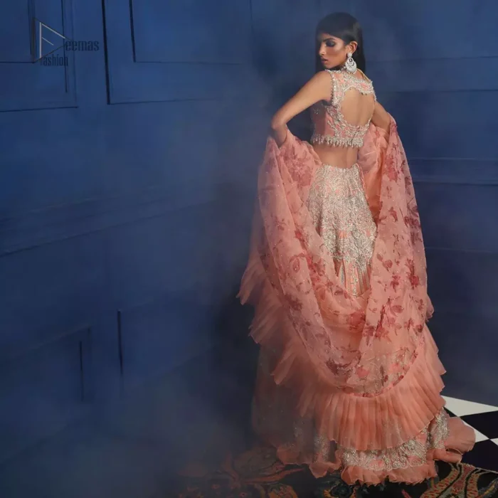 Crafted with love. This outfit is classically designed to make your memorable day beautiful as it should be. The peachy blouse is emphasized with intricate embroidery, handcrafted bootis adorned with silver embellishment finished with dangling pearls all around the edges. Compliment the look with flared lehenga which is decorated with silver kora, dabka, tilla and pearls work. Excellence of craftsmanship is evident with intricate detailing that features the use of zardozi work. The look is complete with organza dupatta finishing with frilled border.