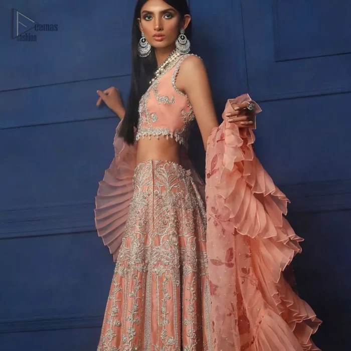 Crafted with love. This outfit is classically designed to make your memorable day beautiful as it should be. The peachy blouse is emphasized with intricate embroidery, handcrafted bootis adorned with silver embellishment finished with dangling pearls all around the edges. Compliment the look with flared lehenga which is decorated with silver kora, dabka, tilla and pearls work. Excellence of craftsmanship is evident with intricate detailing that features the use of zardozi work. The look is complete with organza dupatta finishing with frilled border.