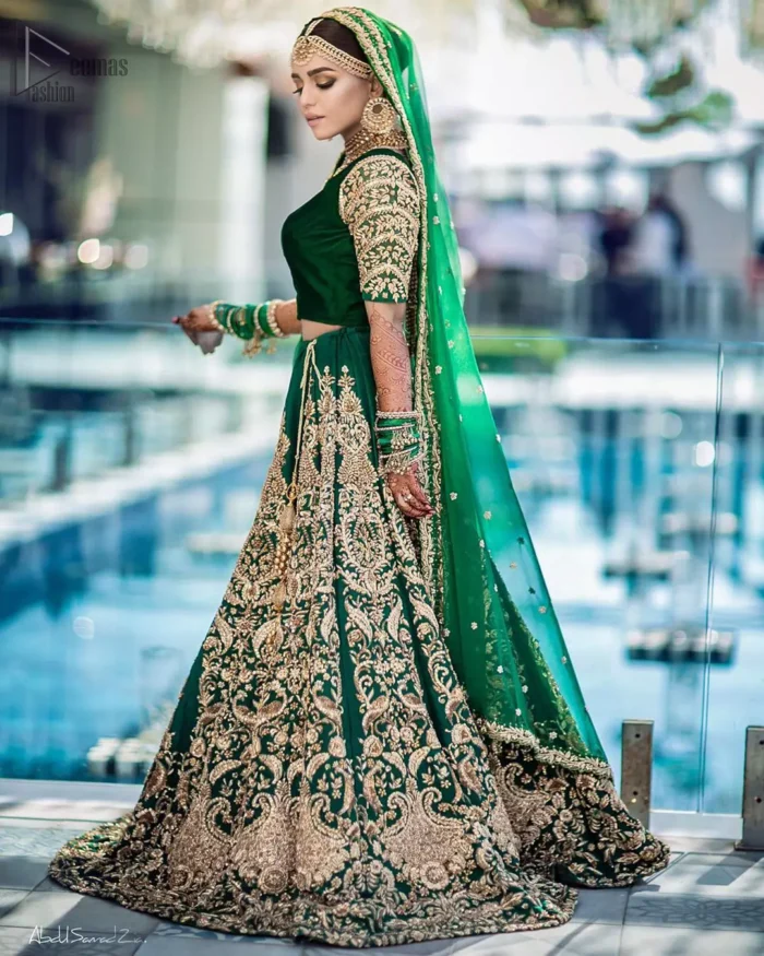 This artisanal piece is rendered in grace and timelessness. This outfit makes a statement in this stunningly floraison, perfect blend of glamour and tradition with outstanding craftsmanship and gorgeous detailing. This mehndi dress in a dreamy shade of green, enhanced with hand embellishments on neckline and sleeves. The wide flared lehenga is an example of remarkable handiwork with a lot of attention to detail. The sculptured embroidery is in the shade of golden. Complete the look with bottle green organza dupatta emphasized with tiny floral motifs on the ground and four sided embellished border.