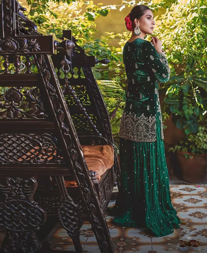 This mehndi outfit is a true example of decorative and ornamental expression stylized in a contemporary way. The dress comes with a bottle green velvet shirt with beautiful embellished motifs on the ground and vertically worked lines and it finished with a thick embellished border with silver zardozi work. Pair it up with bottle green crushed sharara adorned with scattered sequins all over. To complete the look, go with chiffon dupatta decorated with sequins spray all over.