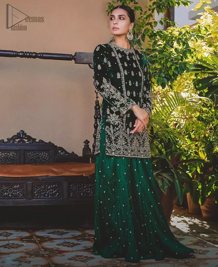 This mehndi outfit is a true example of decorative and ornamental expression stylized in a contemporary way. The dress comes with a bottle green velvet shirt with beautiful embellished motifs on the ground and vertically worked lines and it finished with a thick embellished border with silver zardozi work. Pair it up with bottle green crushed sharara adorned with scattered sequins all over. To complete the look, go with chiffon dupatta decorated with sequins spray all over.