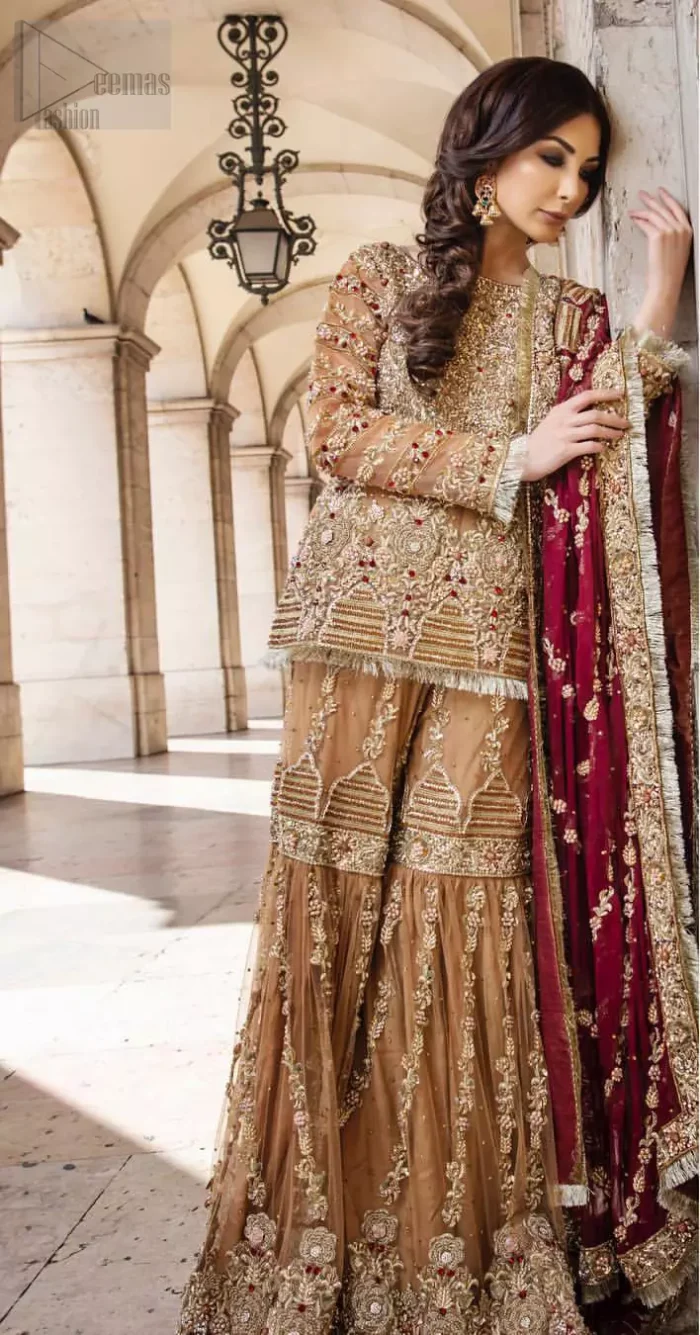 Picturing your bridal in a glowing fawn color. Featuring beautiful handwork, this outfit has a delicate arrangement of hand embellished geometric patterns with pearls and crystals on the bottom. Refined craftsmanship is at its best with hand embellished bodice which is laden with zardozi work. This outfit is paired with organza gharara with embroidered bottom and kiran lace, and maroon dupatta ornamented with geometric patterns along the length, making it a statement piece. Furthermore it is also enhanced with kiran lace on all four sides.
