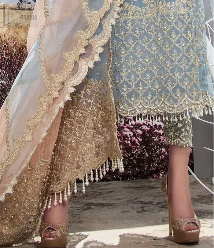 Intricate details, flamboyant silhouettes and mastery of colour are what makes this dress stand out from the rest. This is one of the elegant pieces are sure to stay in your heart and your wardrobe forever. The front of the shirt is beautifully ornamented with floral motifs and bootis, also a delicate arrangement of geometric patterns on the hemline with light golden and silver zardozi work. The back of the shirt is accentuated with a large central motif and scattered tiny floral motifs all over. It comprises with ferozi capri pants emphasized with bottom. To complete the look, go with a gradient dupatta having geometric patterns on pallu and scalloped border along the length. Furthermore the outfit is fully decorated with scalloped finishing and tassels.